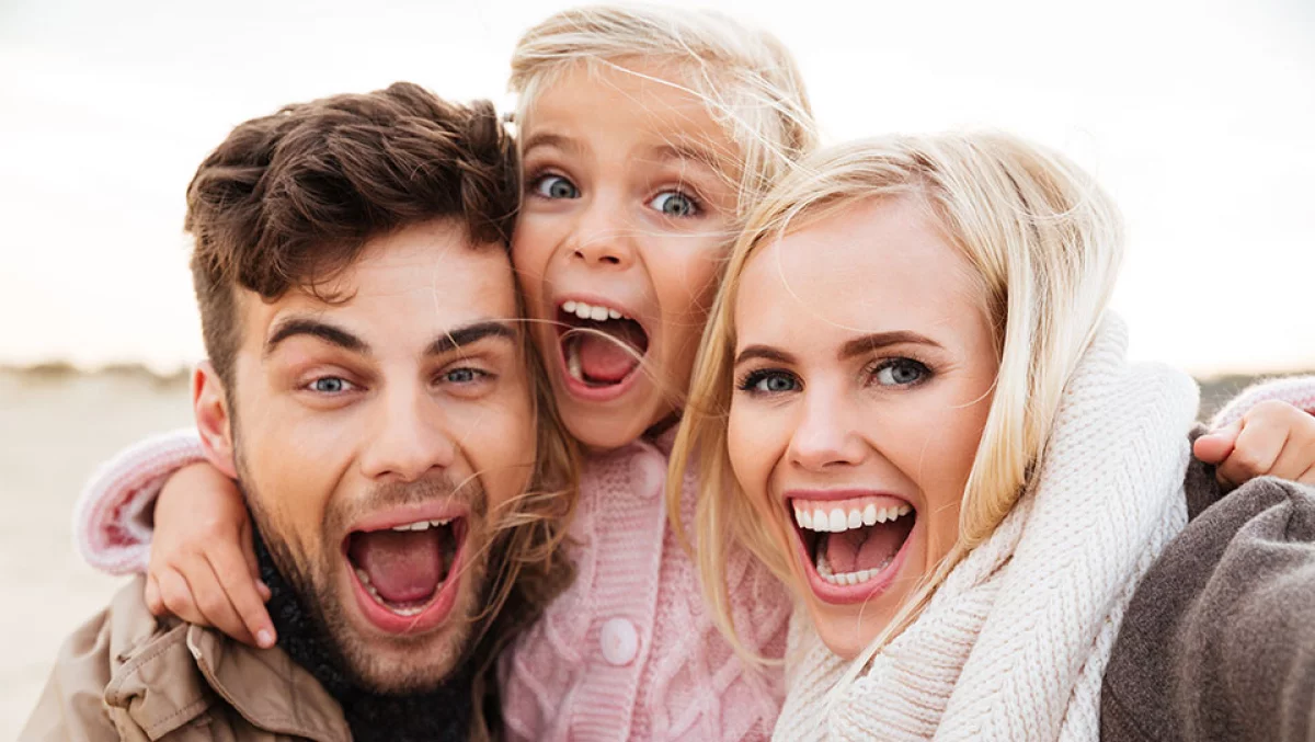 Glückliche Familie mit Kind lacht im Freien​​​​​​​​​​​​