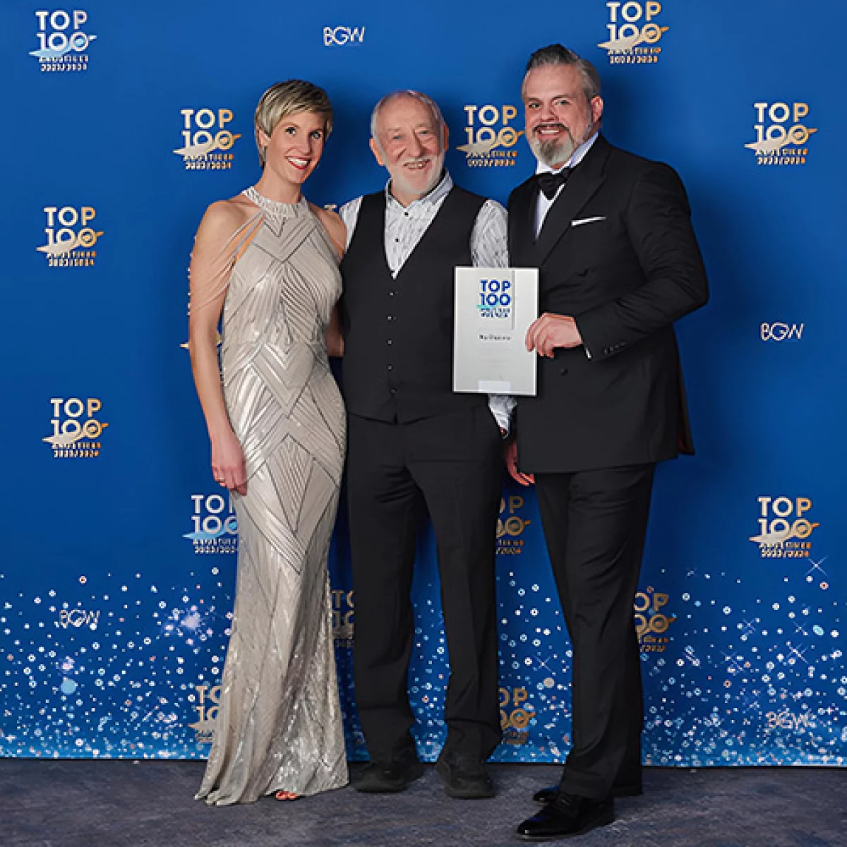 Drei Personen bei Top 100 Hörakustiker Auszeichnung mit Urkunde