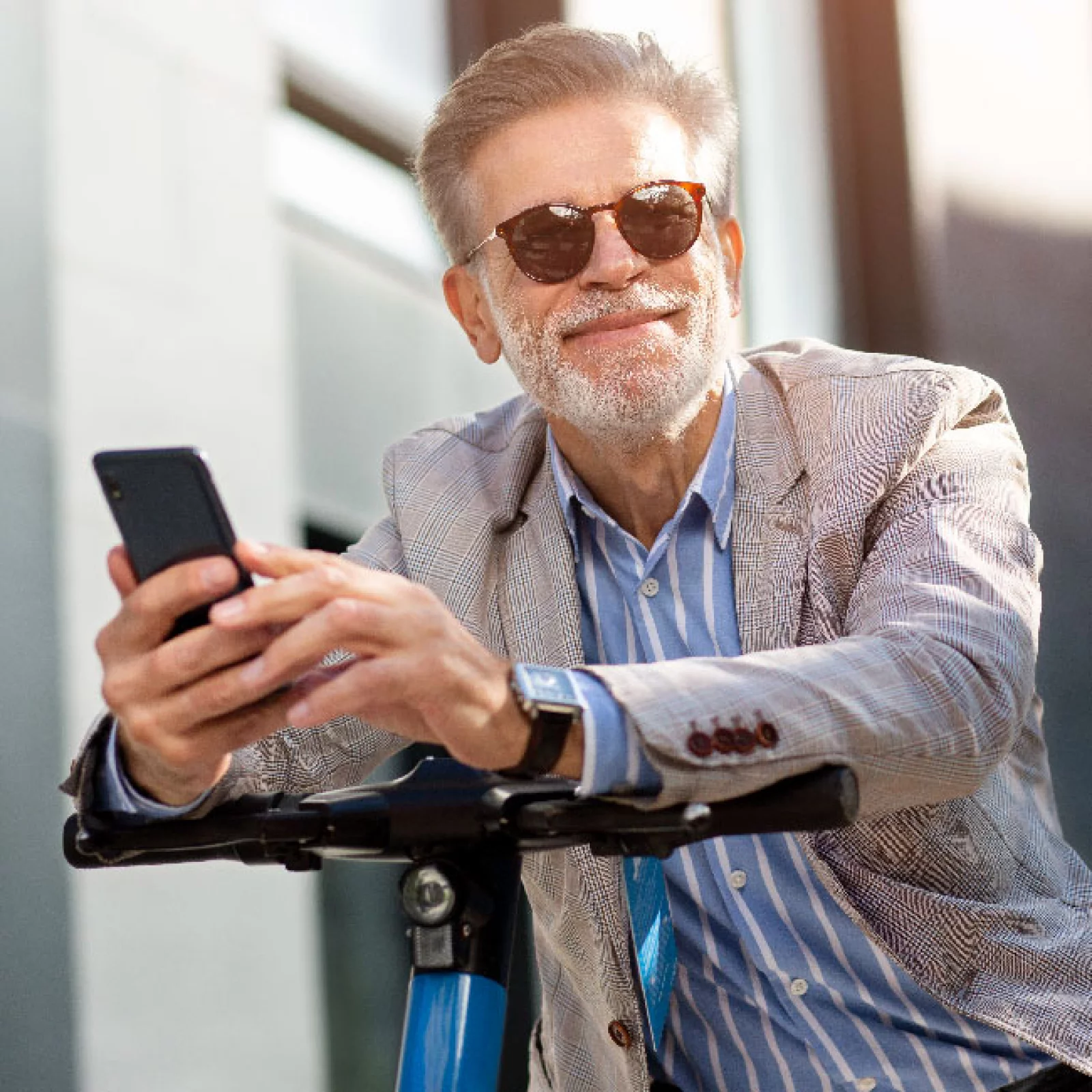 Älterer Mann mit Smartphone und E-Scooter im Freien​​​​