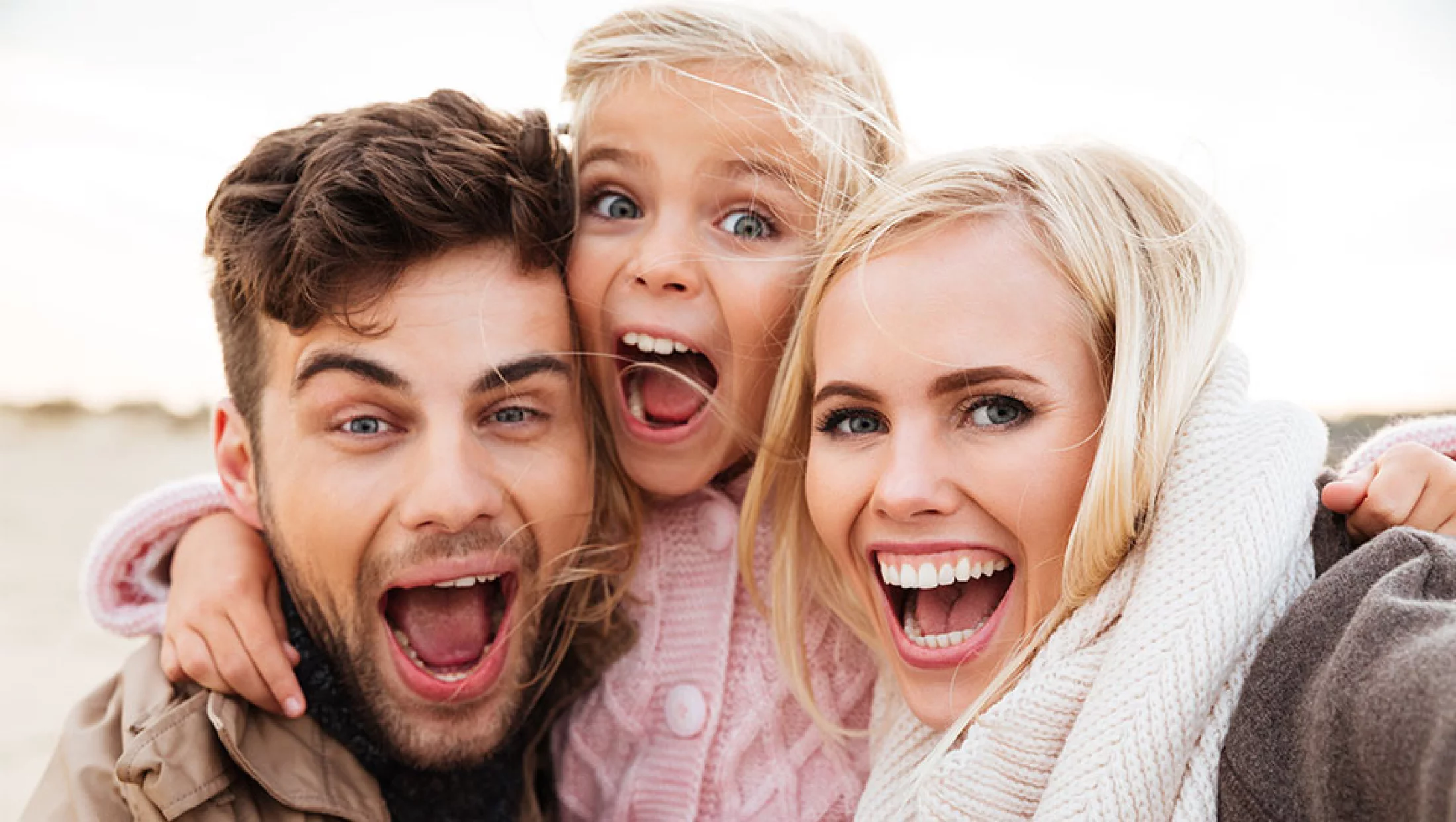 Glückliche Familie mit Kind lacht im Freien​​​​​​​​​​​​