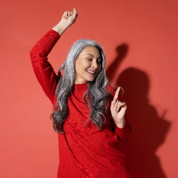 Frau mit grauen Haaren tanzt vor rotem Hintergrund​​​​​
