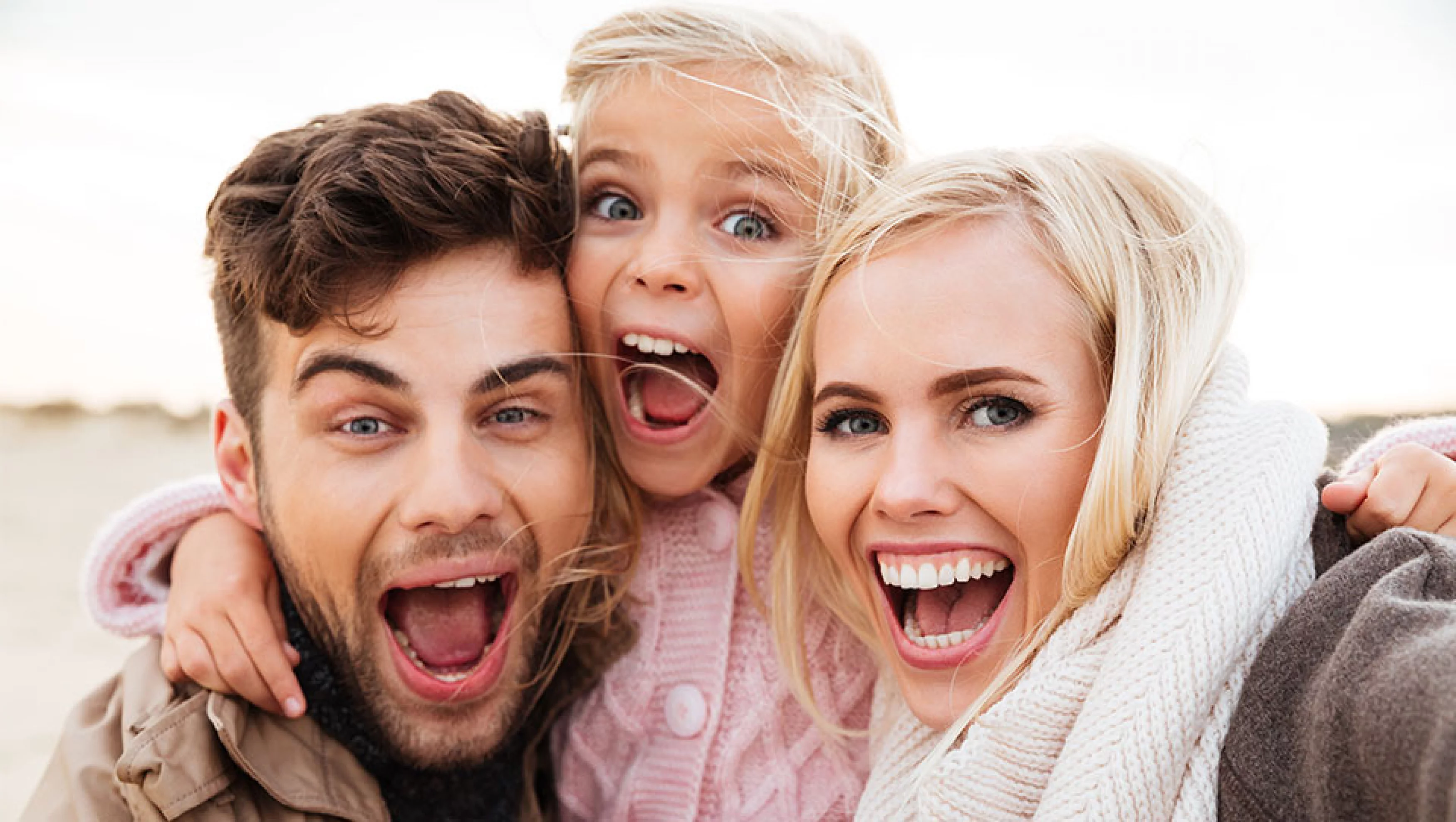 Glückliche Familie mit Kind lacht im Freien​​​​​​​​​​​​