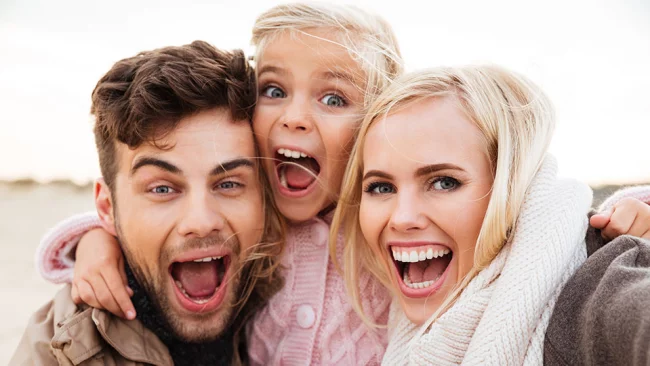 Glückliche Familie mit Kind lacht im Freien​​​​​​​​​​​​