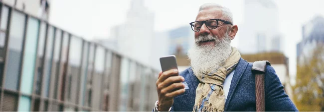 Älterer Mann mit Smartphone und Brille in urbaner Umgebung
