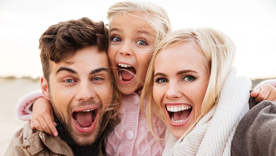 Glückliche Familie mit Kind lacht im Freien​​​​​​​​​​​​