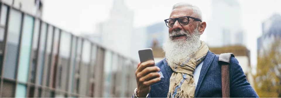 Älterer Mann mit Smartphone und Brille in urbaner Umgebung